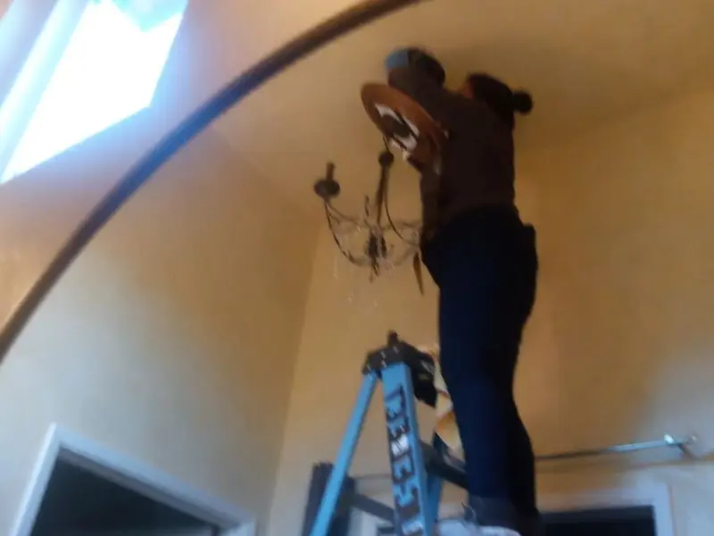 Electrician installing a chandelier in a Waldorf residence